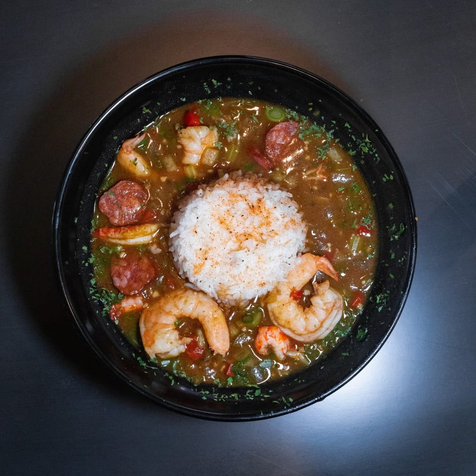 Seafood gumbo with shrimp and sausage over a mound of white rice.