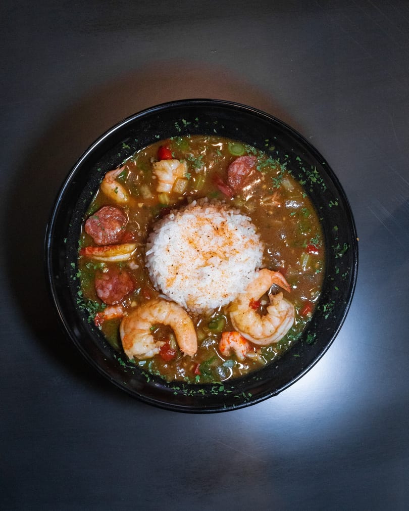 Seafood gumbo with shrimp and sausage over a mound of white rice.
