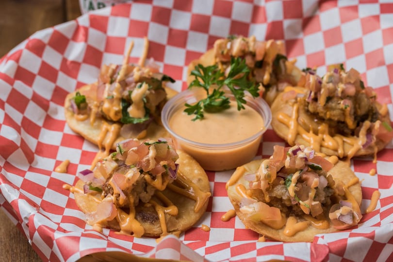 Fried oyster nachos topped with pico de gallo and creamy Cajun sauce.